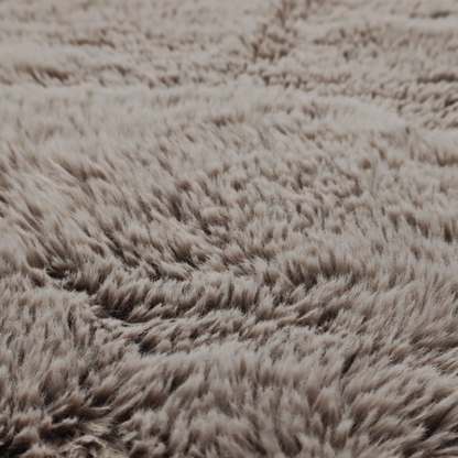 A cool-toned, greyish-brown or charcoal-taupe, high-pile faux fur fabric. It displays a dense, luxurious texture with soft, tousled fibres that create a cosy, shag-inspired look.