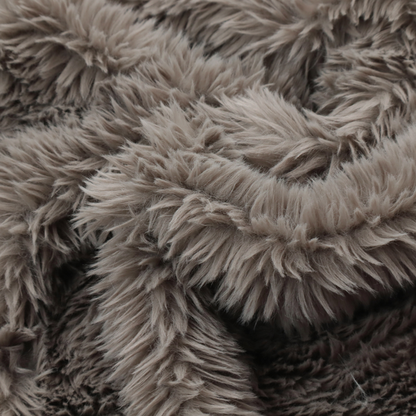 A cool-toned, greyish-brown or charcoal-taupe, high-pile faux fur fabric. It displays a dense, luxurious texture with soft, tousled fibres that create a cosy, shag-inspired look.