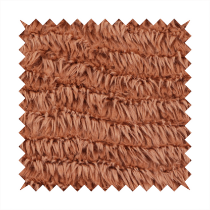 A rust or burnt-orange, high-pile faux fur fabric. It features a unique, wavy or rippled texture created by the directional alignment of the plush, soft fibres, giving it a distinctive shag-like appearance.