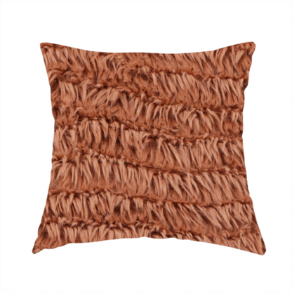The fabric used to create this handmade cushion is a rust or burnt-orange, high-pile faux fur fabric. It features a unique, wavy or rippled texture created by the directional alignment of the plush, soft fibres, giving it a distinctive shag-like appearance.