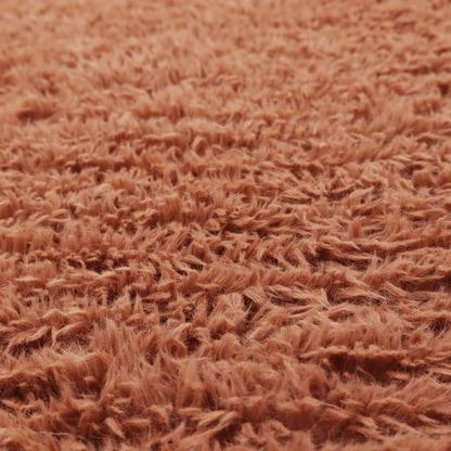 A rust or burnt-orange, high-pile faux fur fabric. It features a unique, wavy or rippled texture created by the directional alignment of the plush, soft fibres, giving it a distinctive shag-like appearance.