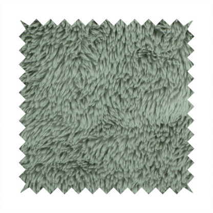 A muted, sage green, high-pile faux fur fabric. It features a dense, luxurious texture with soft, tousled fibres that create a cosy, shag-like appearance.