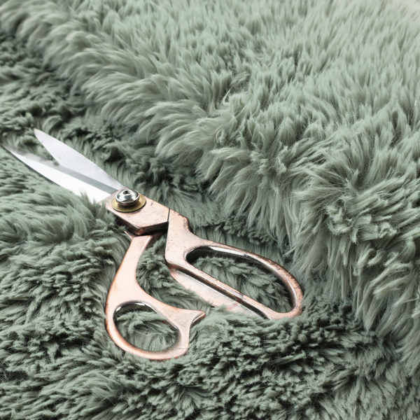 A muted, sage green, high-pile faux fur fabric. It features a dense, luxurious texture with soft, tousled fibres that create a cosy, shag-like appearance.
