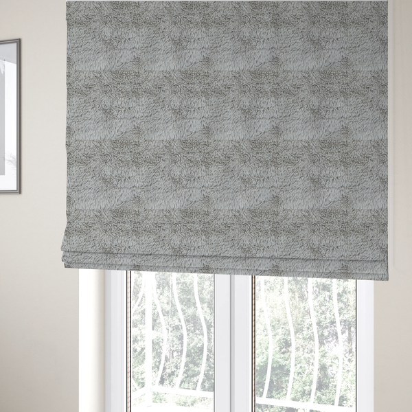 The fabric used to create these Roman blinds is a cool-toned, light silver-grey high-pile faux fur fabric. It has a dense, plush texture characterized by soft, tousled fibres that create a cosy, shag-like appearance.