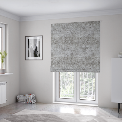 The fabric used to create these Roman blinds is a cool-toned, light silver-grey high-pile faux fur fabric. It has a dense, plush texture characterized by soft, tousled fibres that create a cosy, shag-like appearance.
