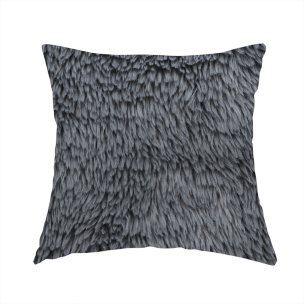 The fabric used to create this handmade cushion is a dark charcoal-grey, high-pile faux fur fabric. It displays a dense, luxurious texture with soft, slightly tousled fibres that create a cosy and sophisticated shag-like appearance.