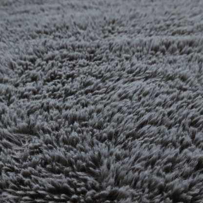 A dark charcoal-grey, high-pile faux fur fabric. It displays a dense, luxurious texture with soft, slightly tousled fibres that create a cosy and sophisticated shag-like appearance.