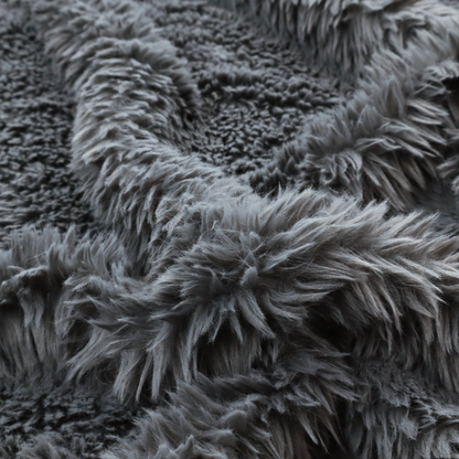 A dark charcoal-grey, high-pile faux fur fabric. It displays a dense, luxurious texture with soft, slightly tousled fibres that create a cosy and sophisticated shag-like appearance.