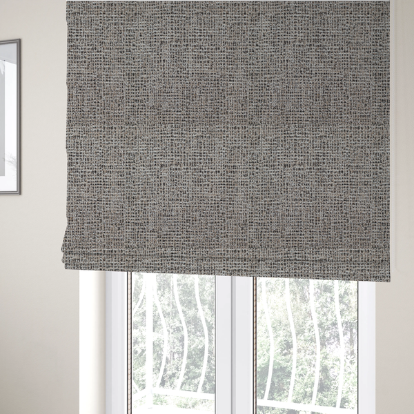 The fabric used to create these Roman blinds is a textured, woven fabric featuring a complex pattern of beige, black, and white threads, creating a speckled and mottled appearance.
