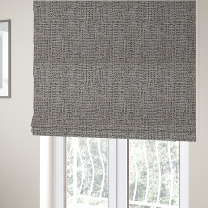 The fabric used to create these Roman blinds is a textured, woven fabric featuring a complex pattern of beige, black, and white threads, creating a speckled and mottled appearance.