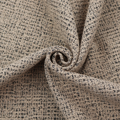 A textured, woven fabric featuring a complex pattern of beige, black, and white threads, creating a speckled and mottled appearance.