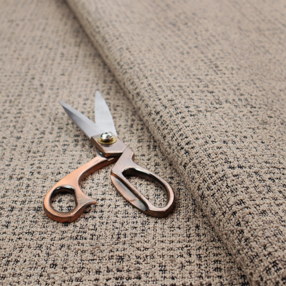 A textured, woven fabric featuring a complex pattern of beige, black, and white threads, creating a speckled and mottled appearance.