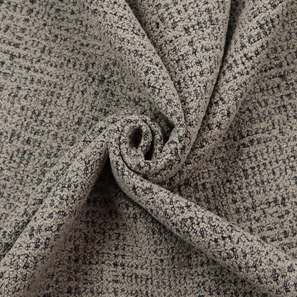 A textured, woven fabric featuring a complex pattern of beige, black, and white threads, creating a speckled and mottled appearance.