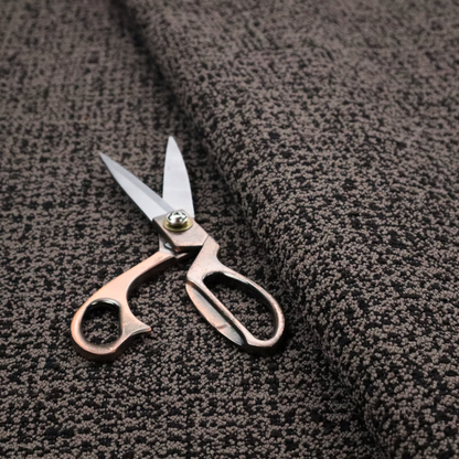 A textured, woven fabric featuring a complex pattern of dark brown, black, and beige threads, creating a speckled and mottled appearance.