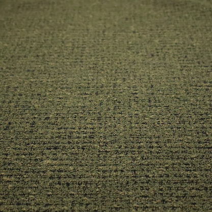 A textured, woven fabric featuring a complex pattern of green, dark, and beige threads, creating a speckled and mottled appearance.