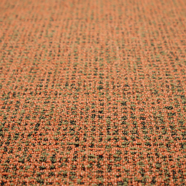 A textured, woven fabric featuring a complex pattern of orange, green, and dark threads, creating a speckled and mottled appearance.