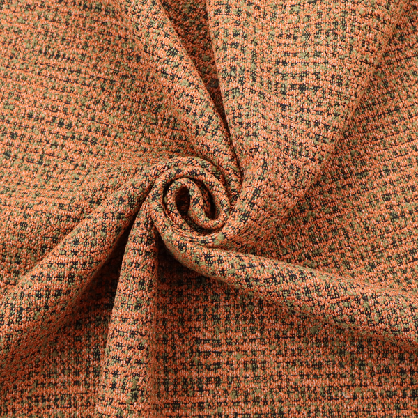 A textured, woven fabric featuring a complex pattern of orange, green, and dark threads, creating a speckled and mottled appearance.
