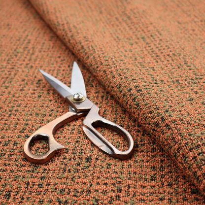 A textured, woven fabric featuring a complex pattern of orange, green, and dark threads, creating a speckled and mottled appearance.