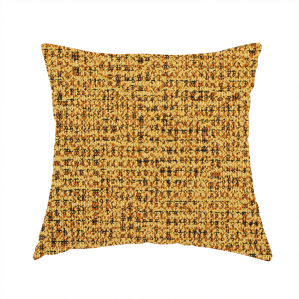 The fabric used to create this handmade cushion is a textured, woven fabric featuring a complex pattern of yellow, dark, and beige threads, creating a speckled and mottled appearance.