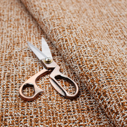 A textured, woven fabric featuring a complex pattern of brown, white, and dark threads, creating a speckled and mottled appearance.