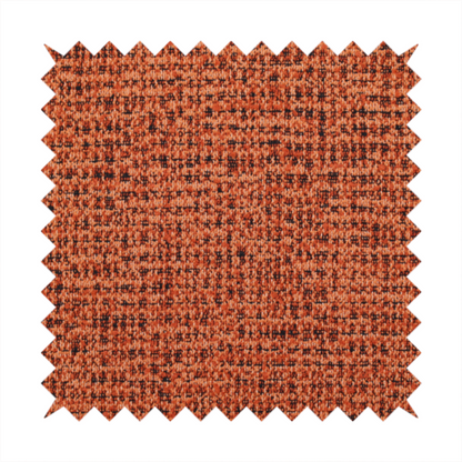 A textured, woven fabric featuring a complex pattern of orange, dark, and beige threads, creating a speckled and mottled appearance.