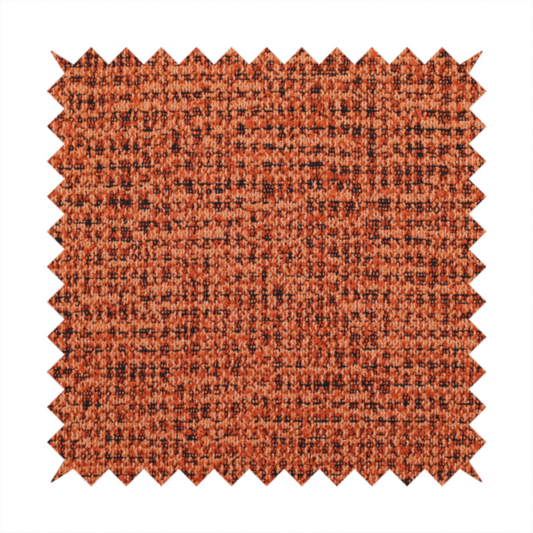 A textured, woven fabric featuring a complex pattern of orange, dark, and beige threads, creating a speckled and mottled appearance.