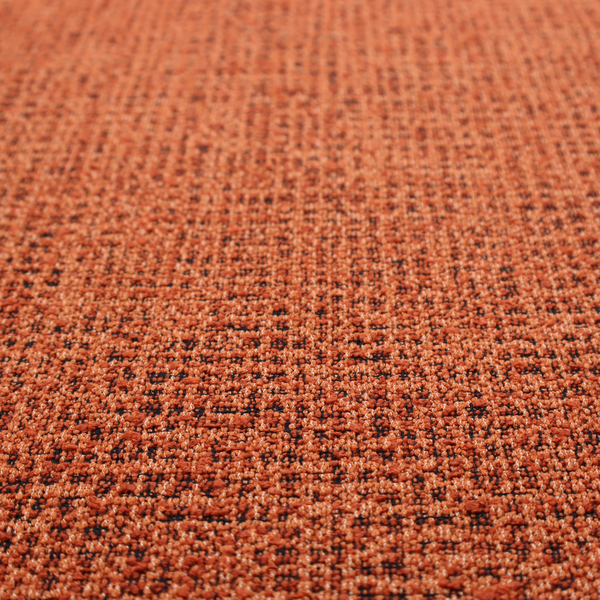 A textured, woven fabric featuring a complex pattern of orange, dark, and beige threads, creating a speckled and mottled appearance.