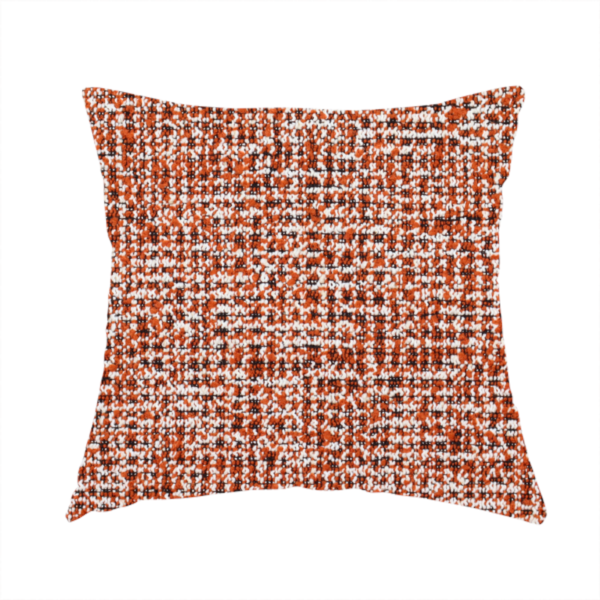 The fabric used to create this handmade cushion is a textured, woven fabric featuring a complex pattern of orange, white, and dark threads, creating a speckled and mottled appearance.