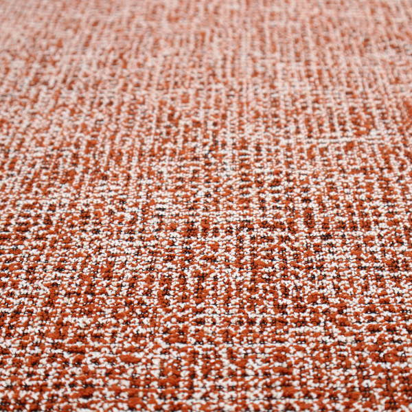 A textured, woven fabric featuring a complex pattern of orange, white, and dark threads, creating a speckled and mottled appearance.