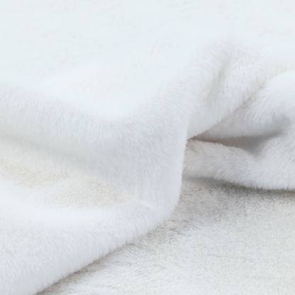A snow-white faux fur. The material has a dense, soft pile with subtle shadows and highlights that showcase its fluffy, velvety texture.