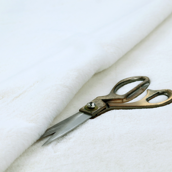 A snow-white faux fur. The material has a dense, soft pile with subtle shadows and highlights that showcase its fluffy, velvety texture.