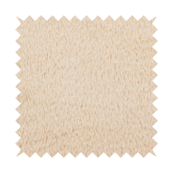 A high-quality faux fur fabric in a warm, sandy beige or light camel hue. The material features a dense, short-pile texture with a soft, uniform grain that gives it a velvety and plush appearance.