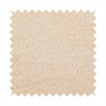 A high-quality faux fur fabric in a warm, sandy beige or light camel hue. The material features a dense, short-pile texture with a soft, uniform grain that gives it a velvety and plush appearance.