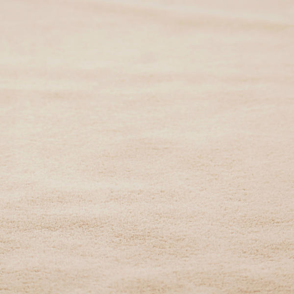 A high-quality faux fur fabric in a warm, sandy beige or light camel hue. The material features a dense, short-pile texture with a soft, uniform grain that gives it a velvety and plush appearance.