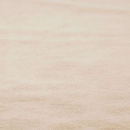 A high-quality faux fur fabric in a warm, sandy beige or light camel hue. The material features a dense, short-pile texture with a soft, uniform grain that gives it a velvety and plush appearance.