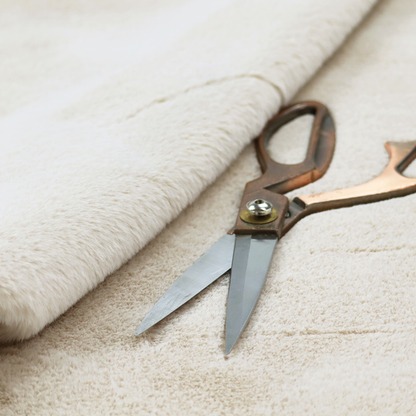 A plush faux fur fabric in a pale oatmeal or light greige shade. The material has a dense, short-pile texture that appears incredibly soft and velvety.