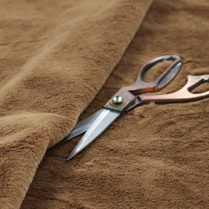 A luxurious faux fur fabric in a rich tobacco or medium brown shade. The material features a dense, velvet-like pile that creates a soft, textured surface with a subtle matte finish. The deep, warm brown colour has a natural-looking depth, with fine fibres that catch the light to reveal a plush, high-density grain.