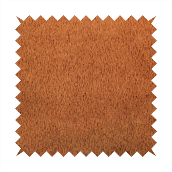 A plush faux fur fabric in a deep, vibrant burnt orange or copper hue. The material displays a dense, short-pile texture that creates a rich, velvet-like appearance. The fibres have a soft, uniform grain that catches the light to reveal warm, glowing undertones, giving the fabric a luxurious sense of depth.