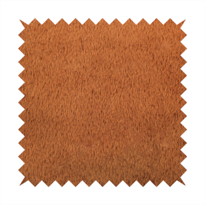 A plush faux fur fabric in a deep, vibrant burnt orange or copper hue. The material displays a dense, short-pile texture that creates a rich, velvet-like appearance. The fibres have a soft, uniform grain that catches the light to reveal warm, glowing undertones, giving the fabric a luxurious sense of depth.