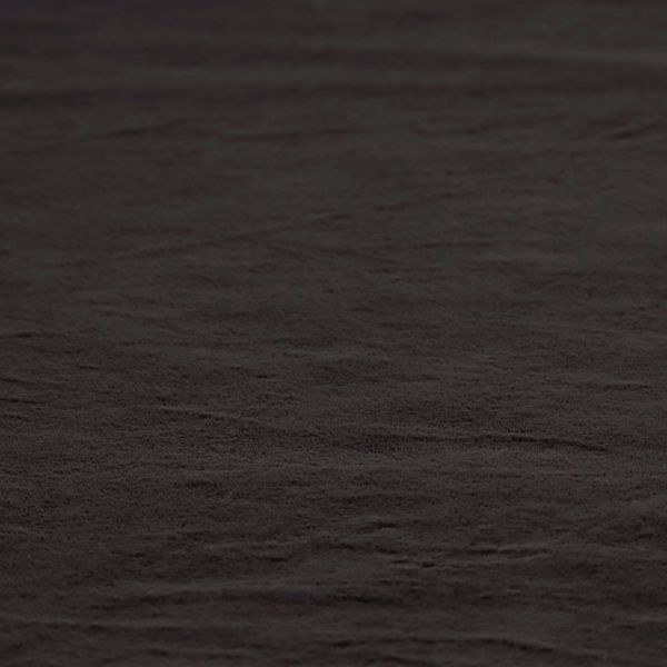 A luxurious faux fur fabric in a deep off-black or charcoal noir shade. The material has an exceptionally dense, short-pile texture that creates a rich, velvet-like surface. The dark fibres catch the light to reveal subtle, cool-toned depth, giving the fabric a sophisticated matte finish.