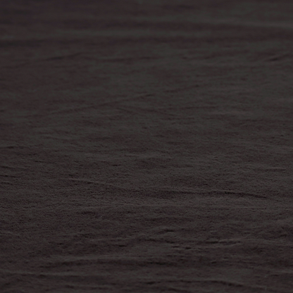 A luxurious faux fur fabric in a deep off-black or charcoal noir shade. The material has an exceptionally dense, short-pile texture that creates a rich, velvet-like surface. The dark fibres catch the light to reveal subtle, cool-toned depth, giving the fabric a sophisticated matte finish.