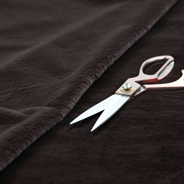 A luxurious faux fur fabric in a deep off-black or charcoal noir shade. The material has an exceptionally dense, short-pile texture that creates a rich, velvet-like surface. The dark fibres catch the light to reveal subtle, cool-toned depth, giving the fabric a sophisticated matte finish.