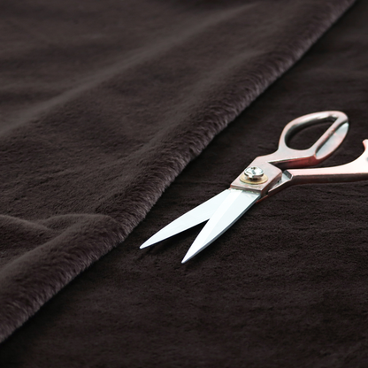 A luxurious faux fur fabric in a deep off-black or charcoal noir shade. The material has an exceptionally dense, short-pile texture that creates a rich, velvet-like surface. The dark fibres catch the light to reveal subtle, cool-toned depth, giving the fabric a sophisticated matte finish.