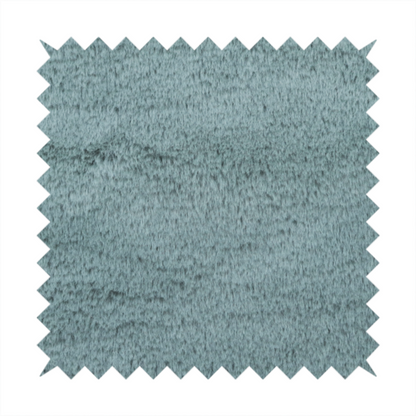 A plush faux fur fabric in a muted dusty teal or slate blue shade. The material has a dense, short-pile texture that creates a soft, uniform surface with a gentle matte sheen. The fibres are tightly packed, showing subtle tonal variations and light shadows that give the fabric a velvety depth.