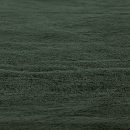 A plush faux fur fabric in a rich forest green or deep pine colour. The material has a dense, short-pile texture that creates a velvety surface with a sophisticated matte finish. The dark green fibres are tightly packed, showing subtle tonal variations and soft shadows that give the fabric a luxurious sense of depth.