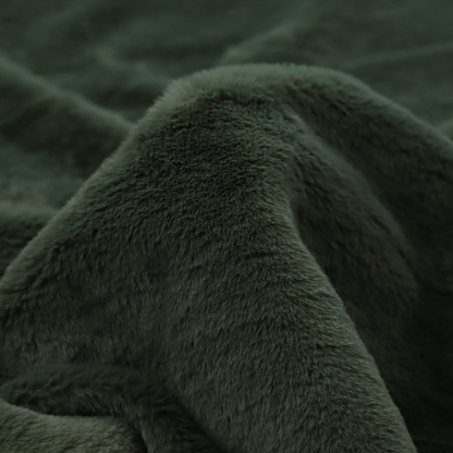 A plush faux fur fabric in a rich forest green or deep pine colour. The material has a dense, short-pile texture that creates a velvety surface with a sophisticated matte finish. The dark green fibres are tightly packed, showing subtle tonal variations and soft shadows that give the fabric a luxurious sense of depth.