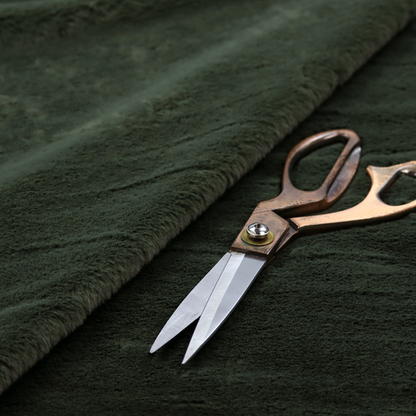 A plush faux fur fabric in a rich forest green or deep pine colour. The material has a dense, short-pile texture that creates a velvety surface with a sophisticated matte finish. The dark green fibres are tightly packed, showing subtle tonal variations and soft shadows that give the fabric a luxurious sense of depth.