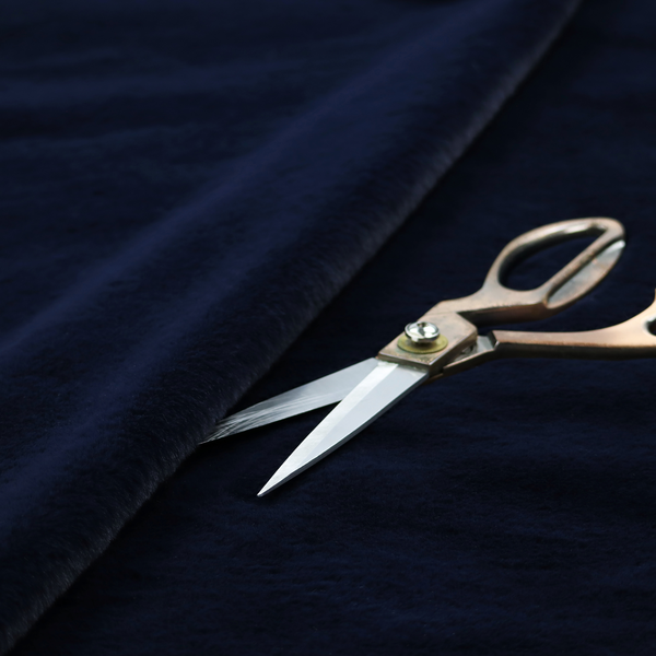 A plush faux fur fabric in a deep, classic navy blue. The material features a dense, short-pile texture that creates a rich, velvety surface with a sophisticated matte finish. The tightly packed dark blue fibres catch the light to show subtle tonal depth and soft shadows, suggesting an exceptionally soft and luxurious hand-feel.