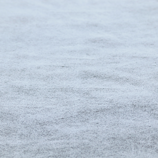 A plush faux fur fabric in a bright silver or icy light grey shade. The material has a dense, short-pile texture that creates a soft, uniform surface with a delicate matte sheen. The cool, pale grey fibres are tightly packed, showing subtle light-and-shadow variations that give the fabric a clean, velvety depth.
