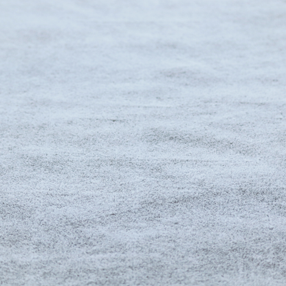 A plush faux fur fabric in a bright silver or icy light grey shade. The material has a dense, short-pile texture that creates a soft, uniform surface with a delicate matte sheen. The cool, pale grey fibres are tightly packed, showing subtle light-and-shadow variations that give the fabric a clean, velvety depth.